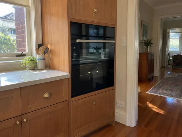 Built-in wall oven in timber kitchen cabinetry beside a hallway in Haberfield